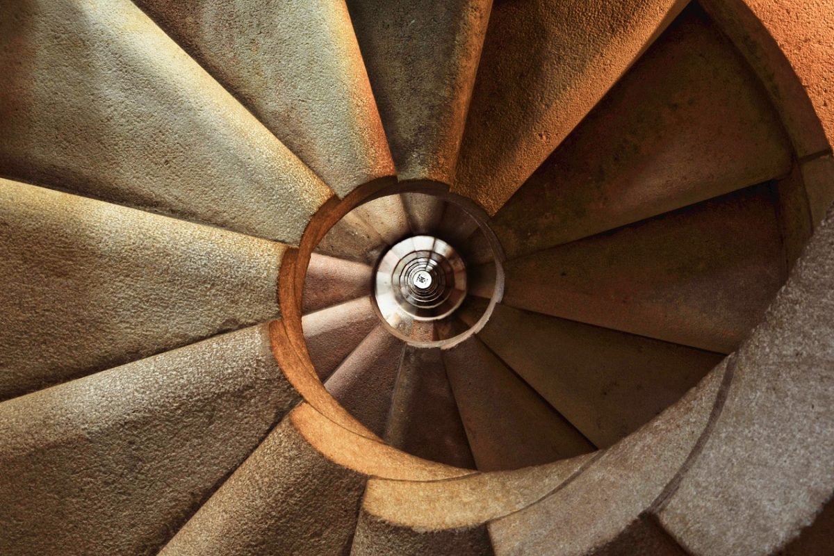 An indoor staircase seen from below, with the handrail running alongside